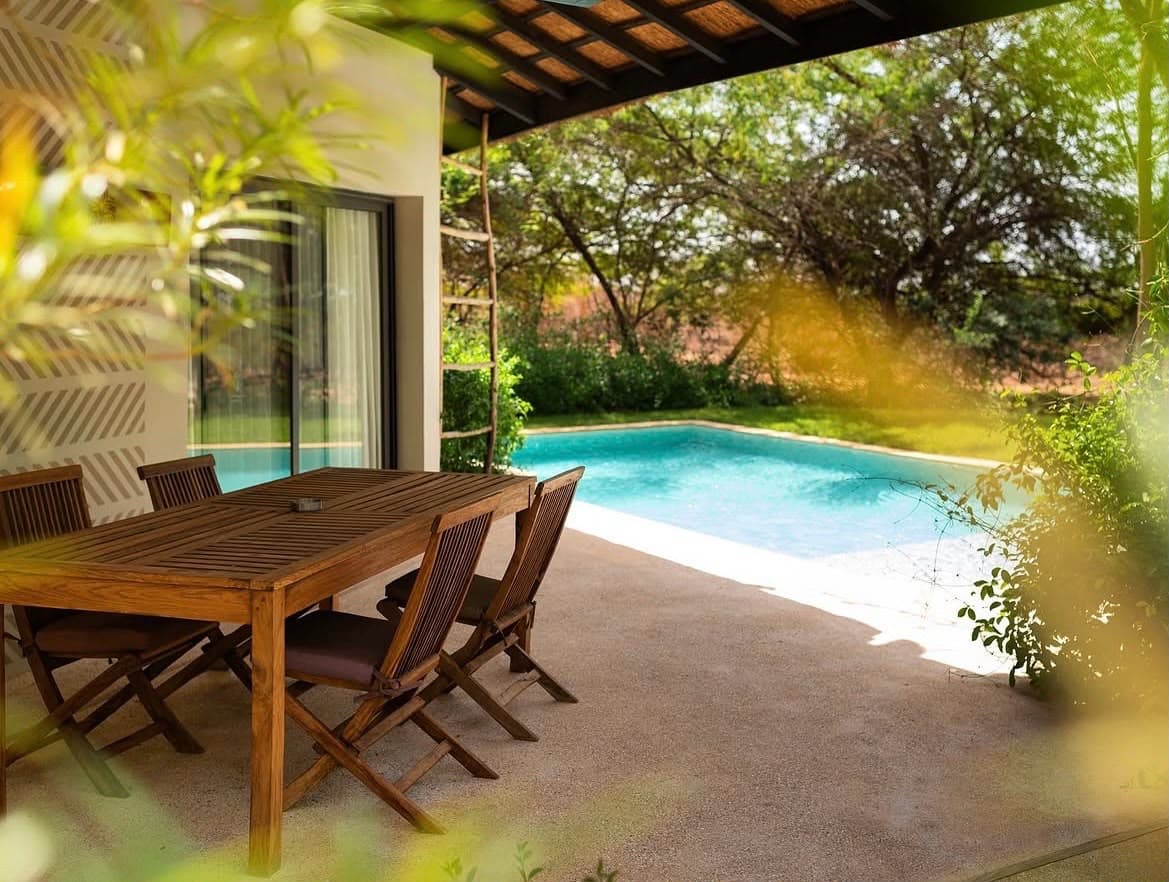 Table en bois sur une terrasse couverte, au bord de la piscine