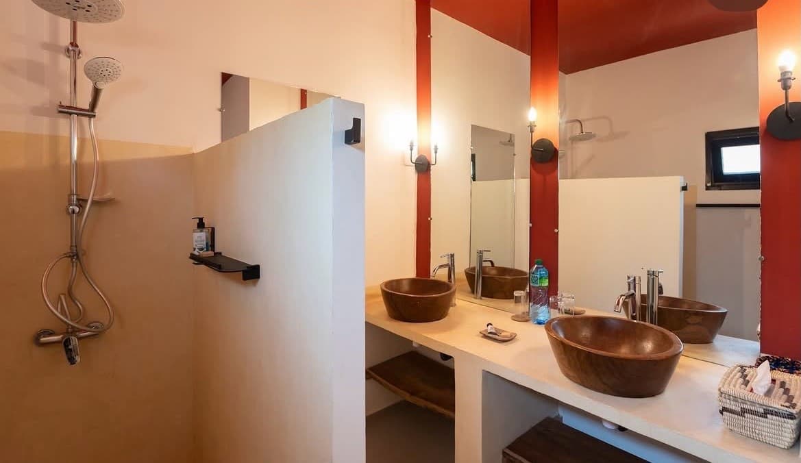 Salle de bain d'un bungalow : vasques en bois sur plan maçonné et douche ouverte