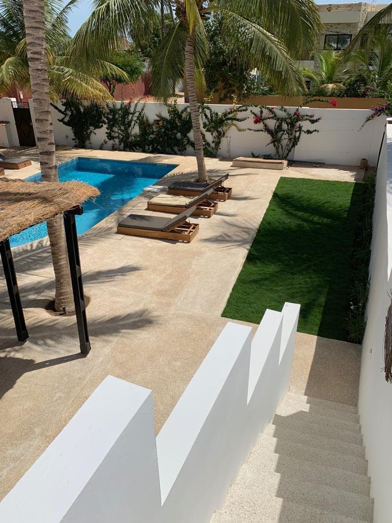 Piscine, allée en pierre et pelouse vues depuis l'escalier de la villa